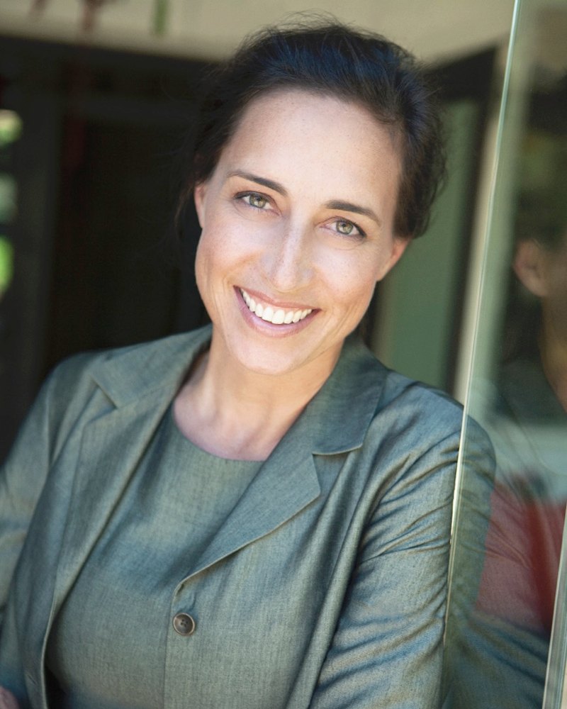 Katherine King, smiling, in a green suit jacket